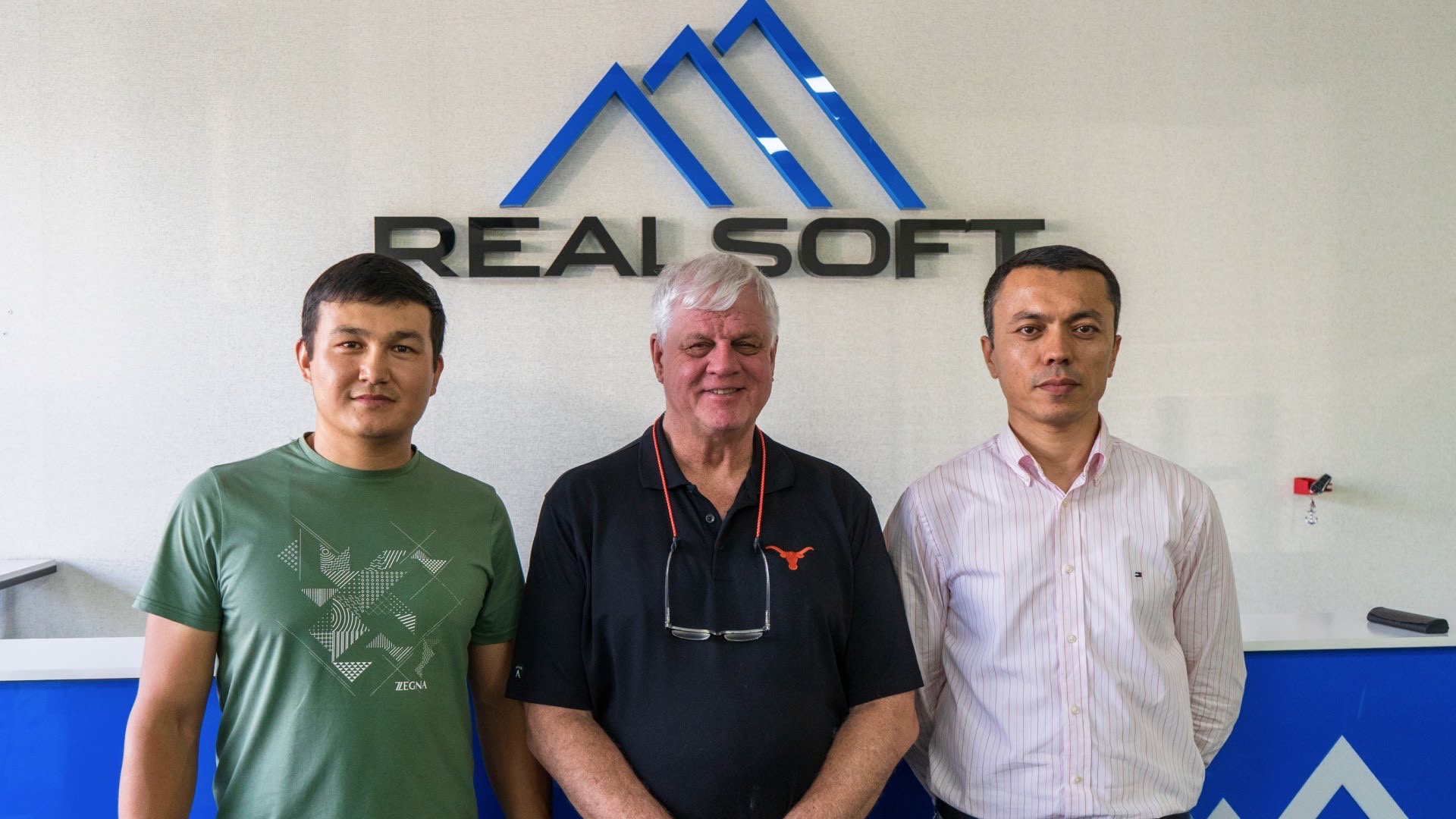 Khurshid Normurodov with RealSoft colleagues and an international partner in front of the RealSoft office sign