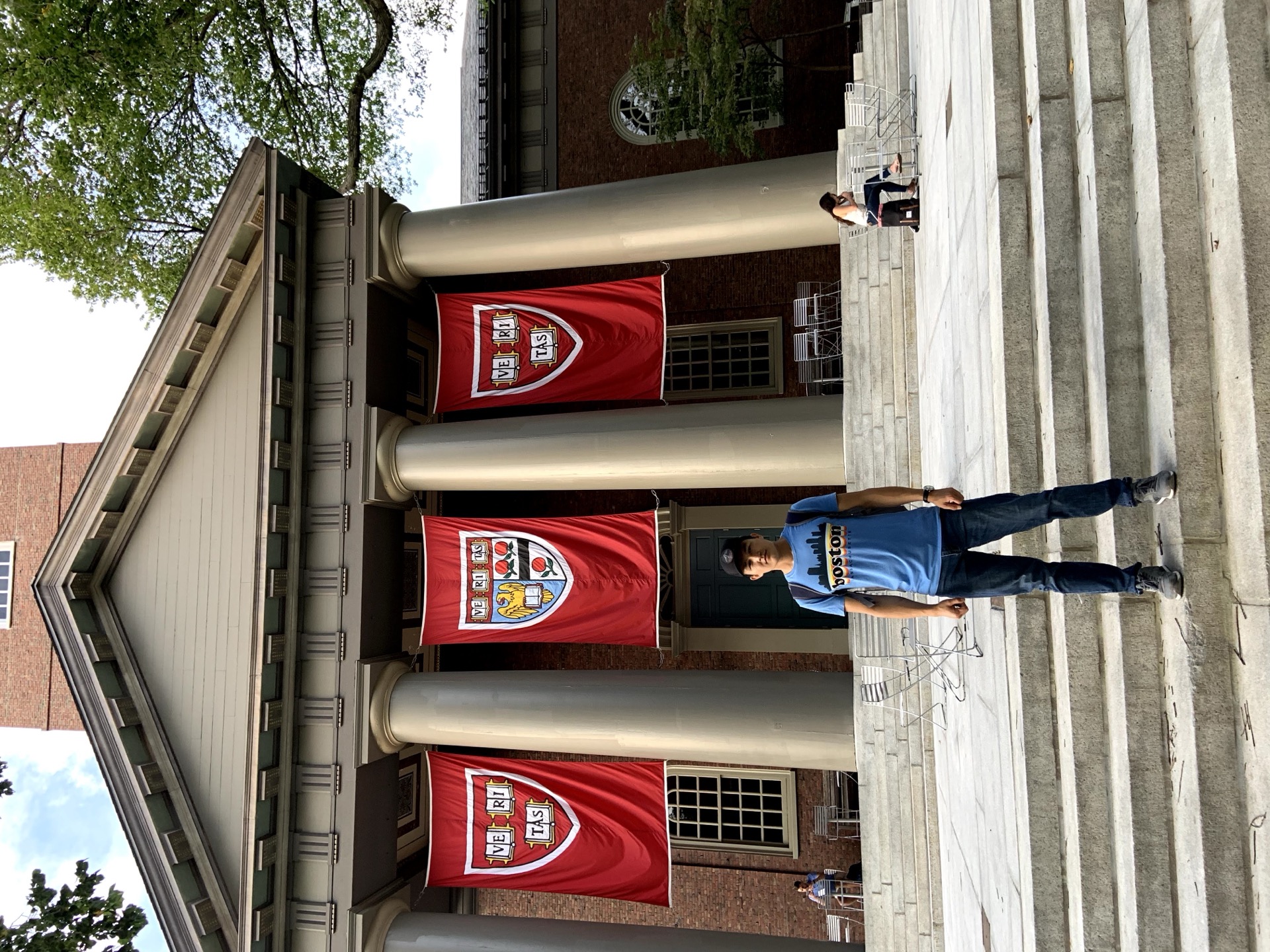 Khurshid Normurodov outside Harvard University's Widener Library with Veritas flags