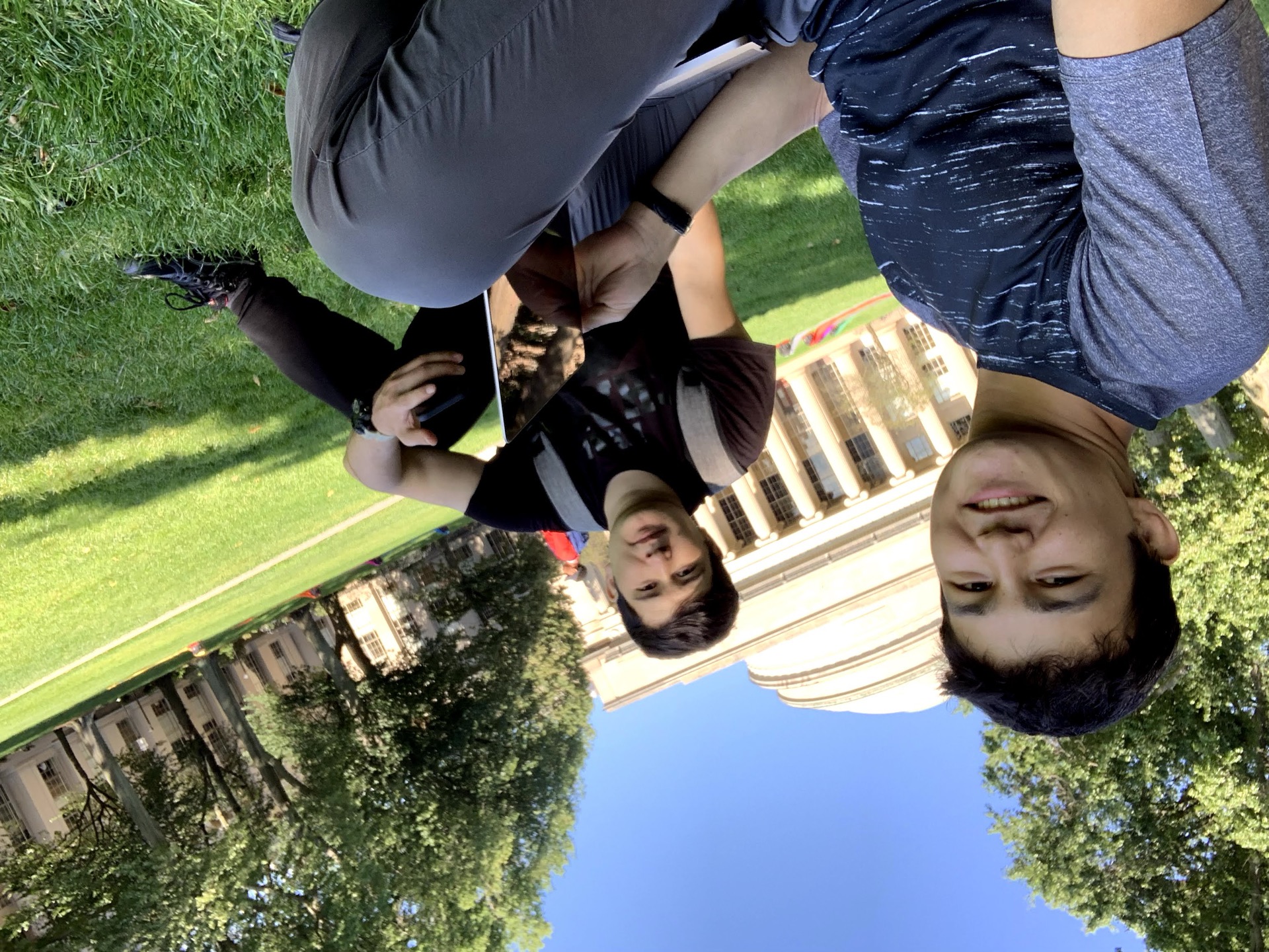 Khurshid Normurodov taking a selfie with a friend on a university campus lawn