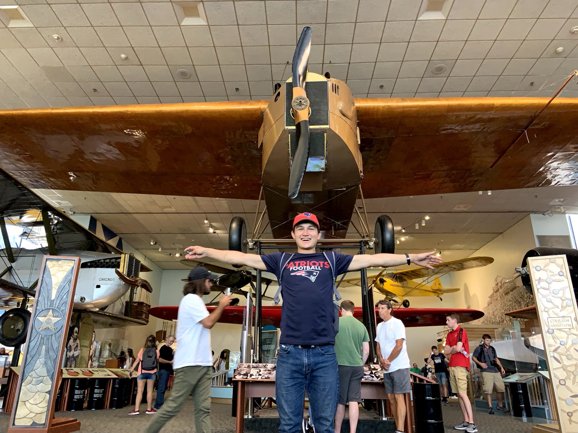 Khurshid Normurodov posing beneath a vintage biplane at an aviation museum