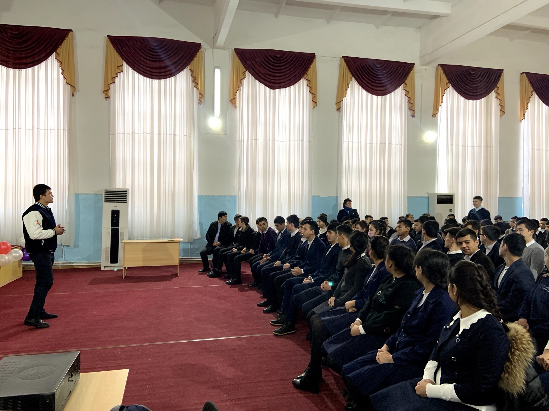 Khurshid Normurodov addressing a hall of school students during an outreach talk