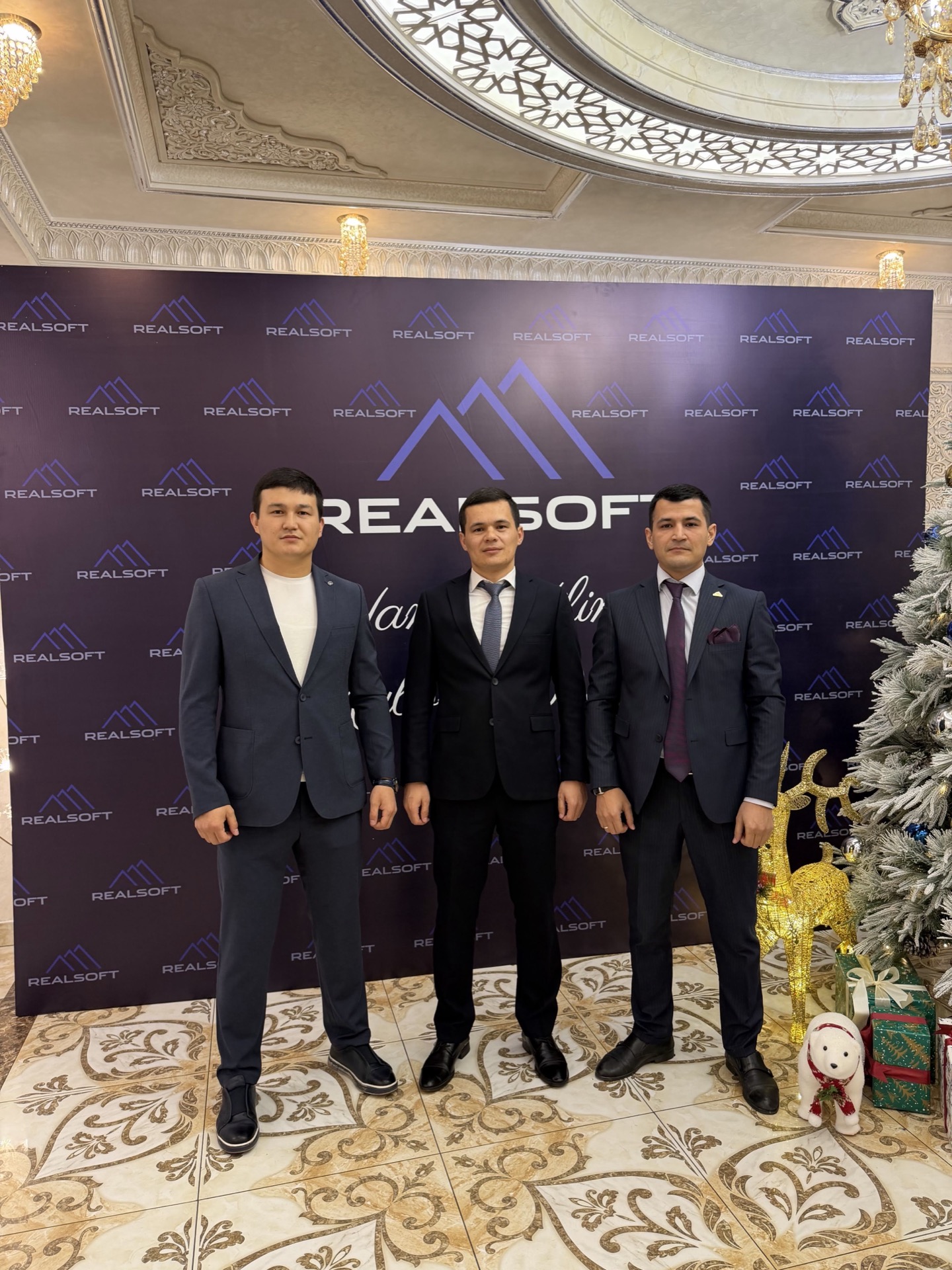 Khurshid Normurodov with RealSoft colleagues at a company gala in front of the RealSoft backdrop