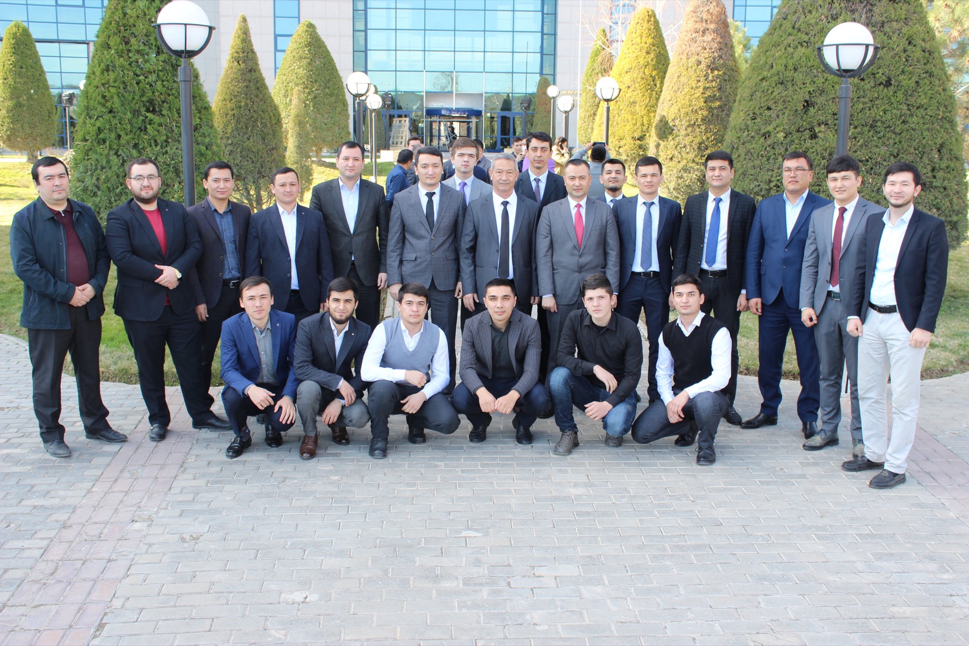 Khurshid Normurodov with a large group of colleagues outside an office building
